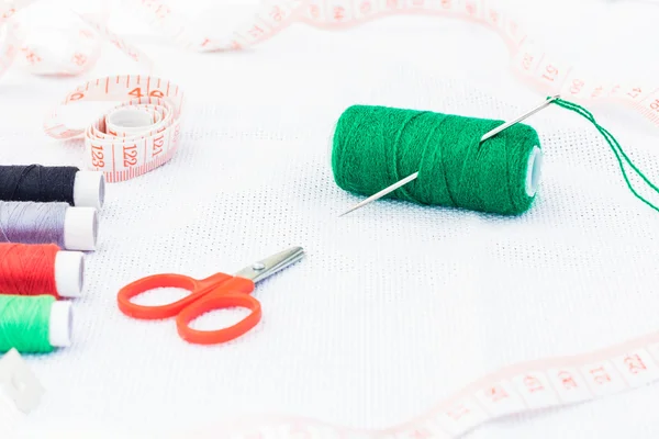 Green spool of thread with needle and scissors — Stock Photo, Image