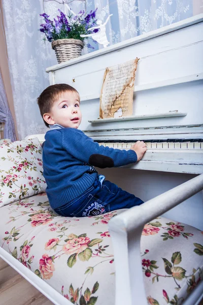 Malý chlapec sedí u klavíru — Stock fotografie