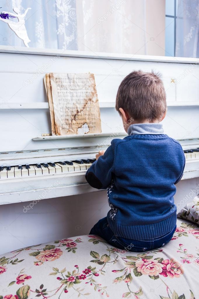 A little boy sits at the piano