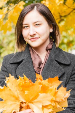 Sonbahar park arka plan yaprakların üzerinde güzel esmer kadın