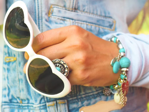Young stylish woman in jeans vest with white heart shaped sunglasses, retro bracelet with turquoise stone, retro ring with turquoise blue stone,summer fashion concept in sunny day — Zdjęcie stockowe