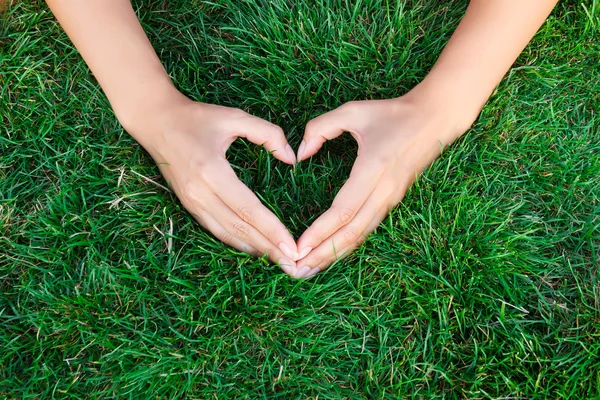 Ręce na trawie w formie heart.hands gospodarstwa zielone serce kształcie trawa / rośliny zielone dziecko ułożone w kształcie serca / miłość natura / uratować świat / leczyć zachowania świata / środowiska — Zdjęcie stockowe