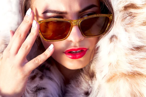 Moda de cerca Retrato de mujer atractiva y elegante con labios rojos con abrigo de piel y gafas de sol retro de moda — Foto de Stock