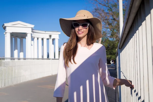 Beautiful young woman walking in the city. Fashion.Wearing cute pink dress,wide hat,cat glasses.Portrait of pretty cheerful woman wearing white dress and straw hat in sunny weather day. — Stock Photo, Image