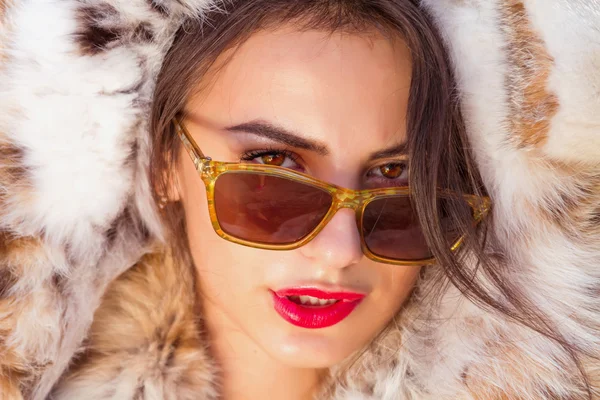 Fashion close up Portrait of attractive stylish woman with red lips wearing fur coat and trendy retro sunglasses — Zdjęcie stockowe