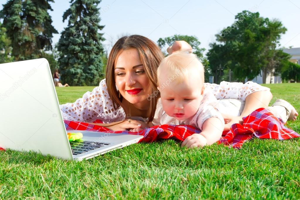 Young mother and baby boy looking into laptop.