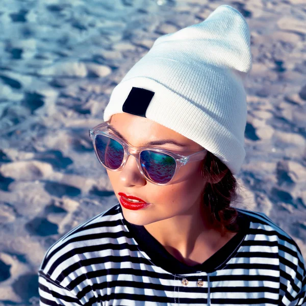 Bella giovane moda donna hipster serio in posa all'aperto in primavera freddo tempo ventoso all'aperto sulla spiaggia vicino al mare — Foto Stock