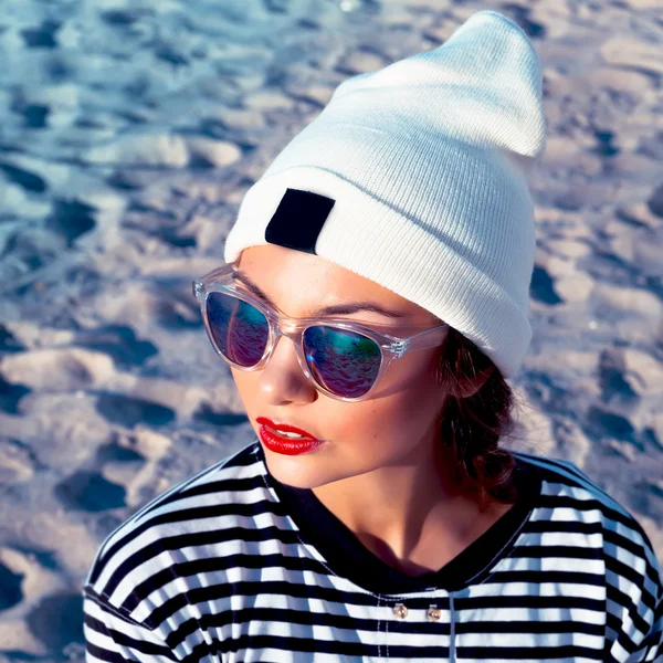 Pretty young fashion serious hipster woman posing outdoor in cold spring windy weather outdoor on the beach near the sea — Zdjęcie stockowe