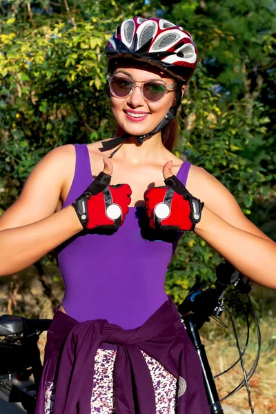 Jovem mulher na bicicleta vestindo no capacete. Capacete de bicicleta mulher colocando capacete de bicicleta no exterior durante o passeio de bicicleta. Mulher vestindo capacete de bicicleta. Close-up retrato de ciclista feminino. — Fotografia de Stock