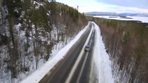 The car rides on a winter road among the woods and mountains — Stock Video