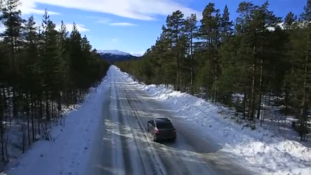 The car rides on a winter road among the woods and mountains — Stock Video