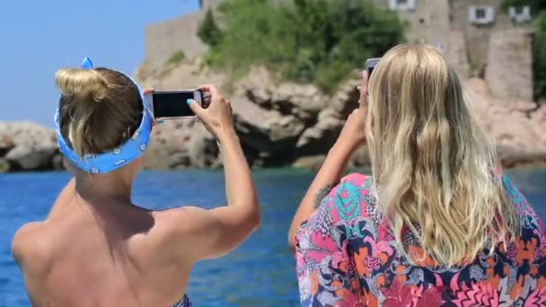 Two girls taking pictures on the phone sitting on the bow of the boat — Stock Video