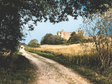 Estonya 'daki eski taş kale. Fırtına geliyormuş. Denizin üzerindeki kara bulutlar. Çayırda yalnız bir kale. Çimen denizi.