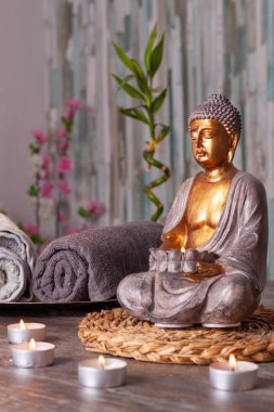 Masada iki havlu ve arka planda dikey bir bambu olan bir Buda resmi.