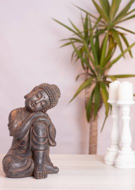 Beyaz arka planda beyaz bir masada iki beyaz mum ve bir bitki.. 