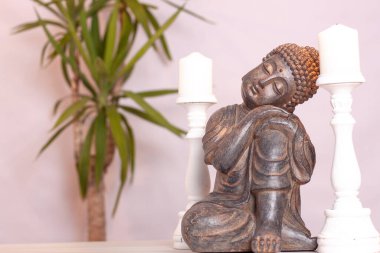 Beyaz arka planda beyaz bir masada iki beyaz mum ve bir bitki.. 