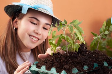 Bahçe için küçük bitkilerle ilgilenen gülümseyen bir kızın yüzü..