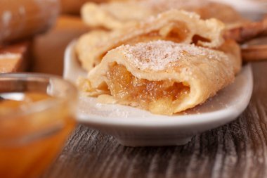 Gri masa örtüsü üzerinde beyaz bir tabakta karamelize kremayla dolu hamur köftelerinin yakın çekim görüntüsü.