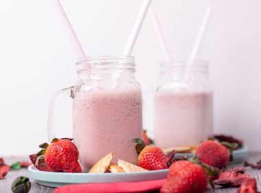 Kavanozların etrafında çilekli içecekler ve turkuaz tabaklar ve çilek parçaları olan kavanozlarda kurabiyeler.