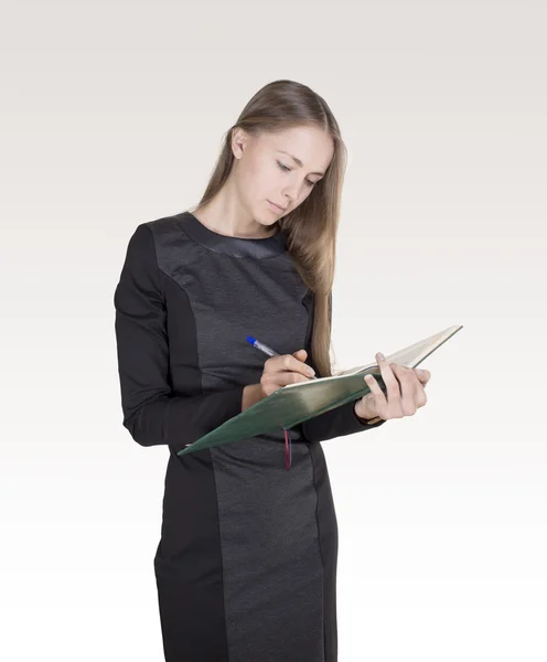 Junge kaukasische Frau mit einem grünen Notizblock in der Hand, der etwas schreibt — Stockfoto