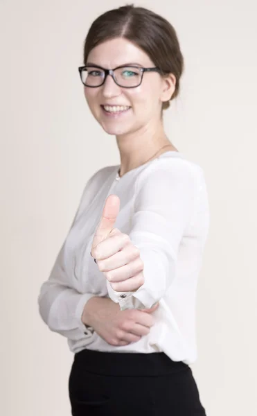 Femme d'affaires souriante avec des lunettes en chemise blanche et jupe noire montrant les pouces vers le haut. focus sur la main — Photo