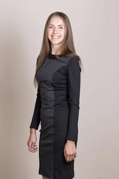 Atractiva joven sonriente en un vestido negro mirando a la cámara . —  Fotos de Stock