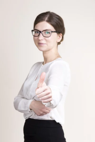 Femme d'affaires souriante avec des lunettes en chemise blanche et jupe noire montrant les pouces vers le haut. focus sur la main — Photo