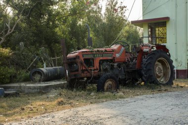 Yol kenarında duran paslı kırmızı bir traktör..