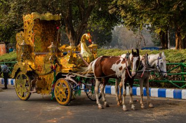 Kolkata, Hindistan, 25 Aralık 2020. İki atlı altın bir at arabası hayal edin ve iki kişi sürüşün tadını çıkarsın..