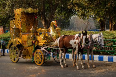 Kolkata, Hindistan, 25 Aralık 2020. İki atlı altın bir at arabası hayal edin ve iki kişi sürüşün tadını çıkarsın..