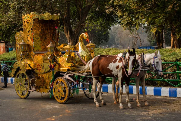 Kolkata, Hindistan, 25 Aralık 2020. İki atlı altın bir at arabası hayal edin ve iki kişi sürüşün tadını çıkarsın..