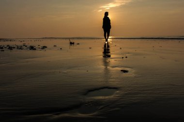 Deniz sahilinde yürüyen altın renkli ışıktaki kadın model. Seçici bir odak noktası.