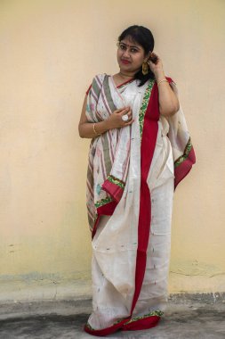 Geleneksel Bengali sarisi içinde güzel bir Hint kadın modeli. Sarı arka planda gülümseyen hafif bir yüzle ve metin için kopya alanı ile mutlu görünüyor. Neşeli ruh hali