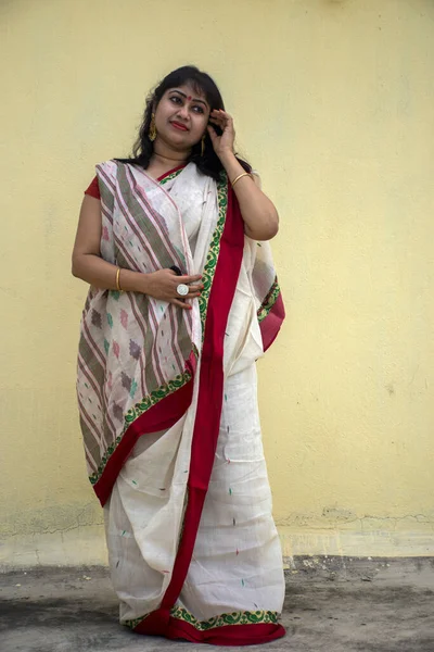 Geleneksel Bengali sarisi içinde güzel bir Hint kadın modeli. Sarı arka planda gülümseyen hafif bir yüzle ve metin için kopya alanı ile mutlu görünüyor. Neşeli ruh hali