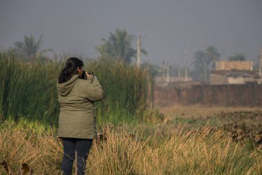 Kolkata yakınlarındaki bir göl ve sulak arazinin güzel manzarasını çeken genç bir bayan. Seçici odak.