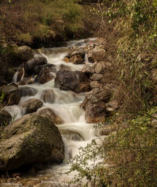Kuzey Sikkim, Hindistan 'ın yosunlu yeşil kayalarıyla güzel bir su manzarası düşüyor. Seçici odak ile uzun pozlama.