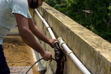 22 Mayıs 2021, Kolkata, Batı Bengal, Hindistan: Erkek bir tesisatçı ince bir kabloyla PVC borularını temizliyor. Seçici odak.