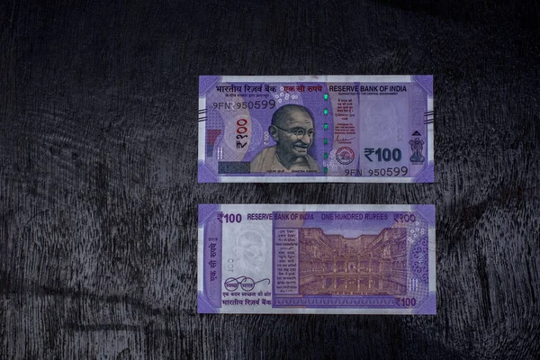 Siyah arka planda 100 rupilik Hint para birimi banknotları. Seçici odak.