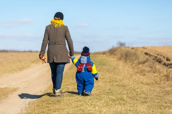 Moeder en zoon wandelen door zandstrand landelijke weg — Stockfoto