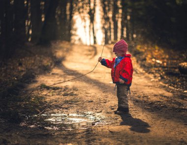 Bahar orman su birikintisine oynayan mutlu beyaz çocuk
