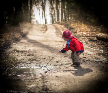 Bahar orman su birikintisine oynayan mutlu beyaz çocuk
