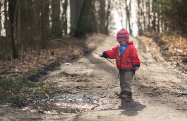 Bahar orman su birikintisine oynayan mutlu beyaz çocuk