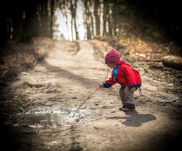 Feliz chico caucásico jugando en el charco en el bosque de primavera — Foto de Stock