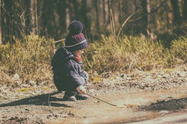 Küçük çocuk su birikintisine baharda oynarken