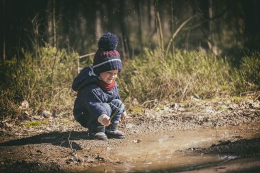 Küçük çocuk su birikintisine baharda oynarken