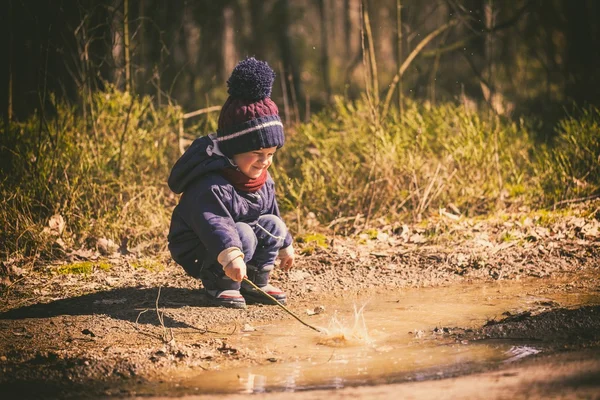 Niño jugando en charco en primavera — Foto de Stock