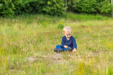 Çayır üzerinde açık oynayan küçük beyaz çocuk