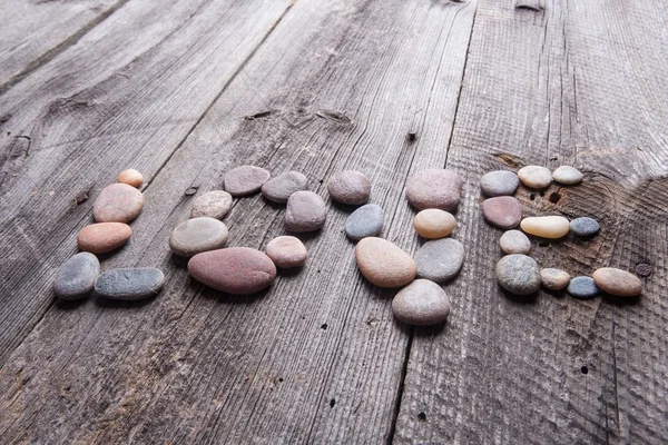 Love inscription made of small stones on wooden table — Stock Photo, Image