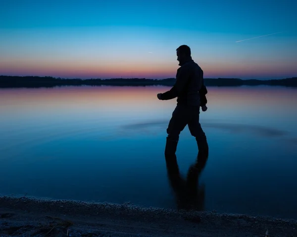 Mann steht bei Sonnenuntergang im Seewasser — Stockfoto