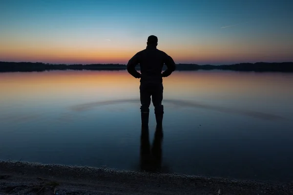 Mann steht bei Sonnenuntergang im Seewasser — Stockfoto